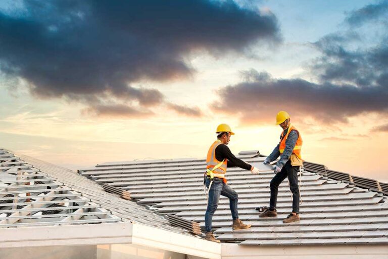 A person applying a protective roof coating to a flat residential rooftop using a roller.